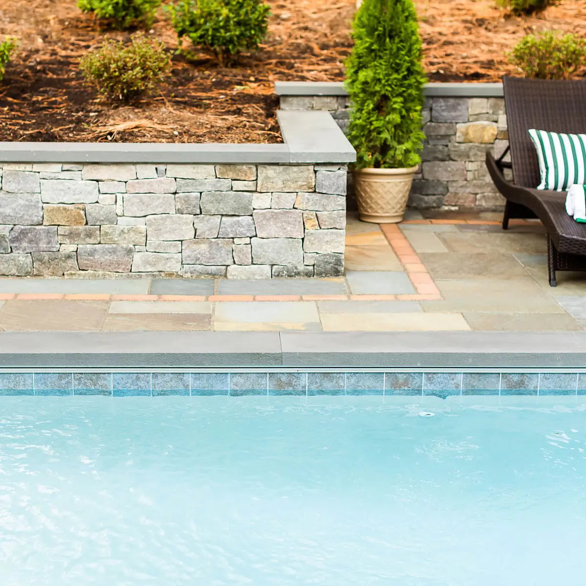 beautifully laid paver patio between retaining wall and underground pool