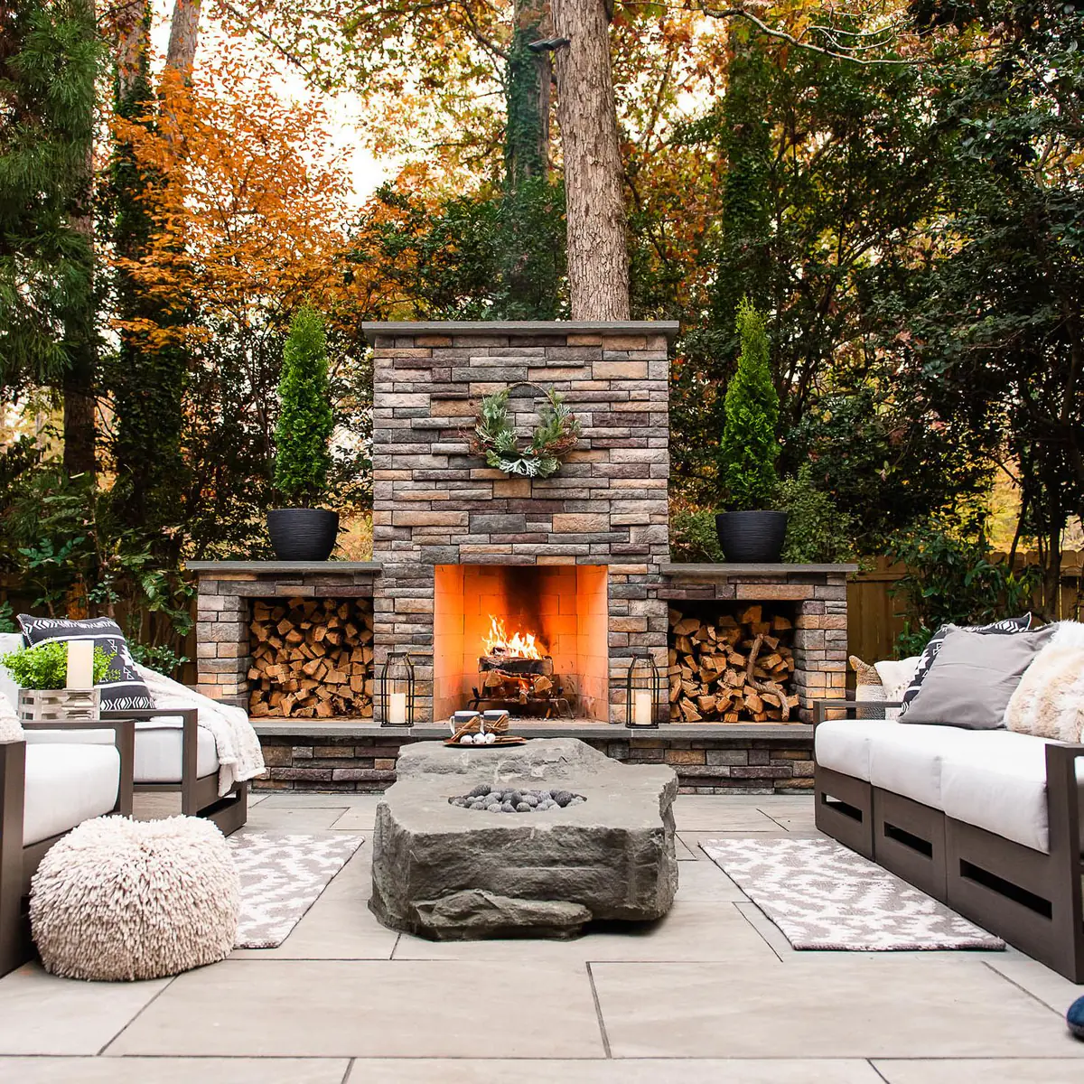 stunning three-part stacked stone veneer fireplace outside with space for storing logs
