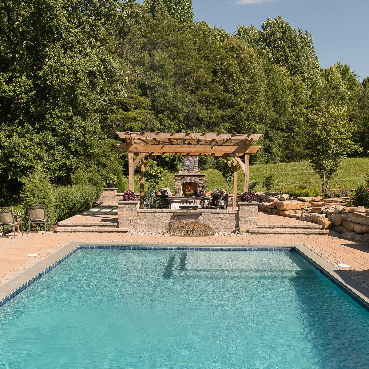 Gunite pool with paver pool decking, fireplace, and pergola