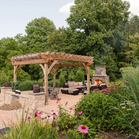 paver patio with pergola, outdoor fireplace, and native landscaping